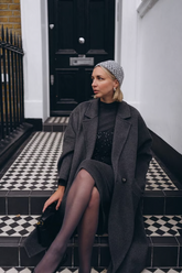 a lady in a black long wool coat and a black sequin dress